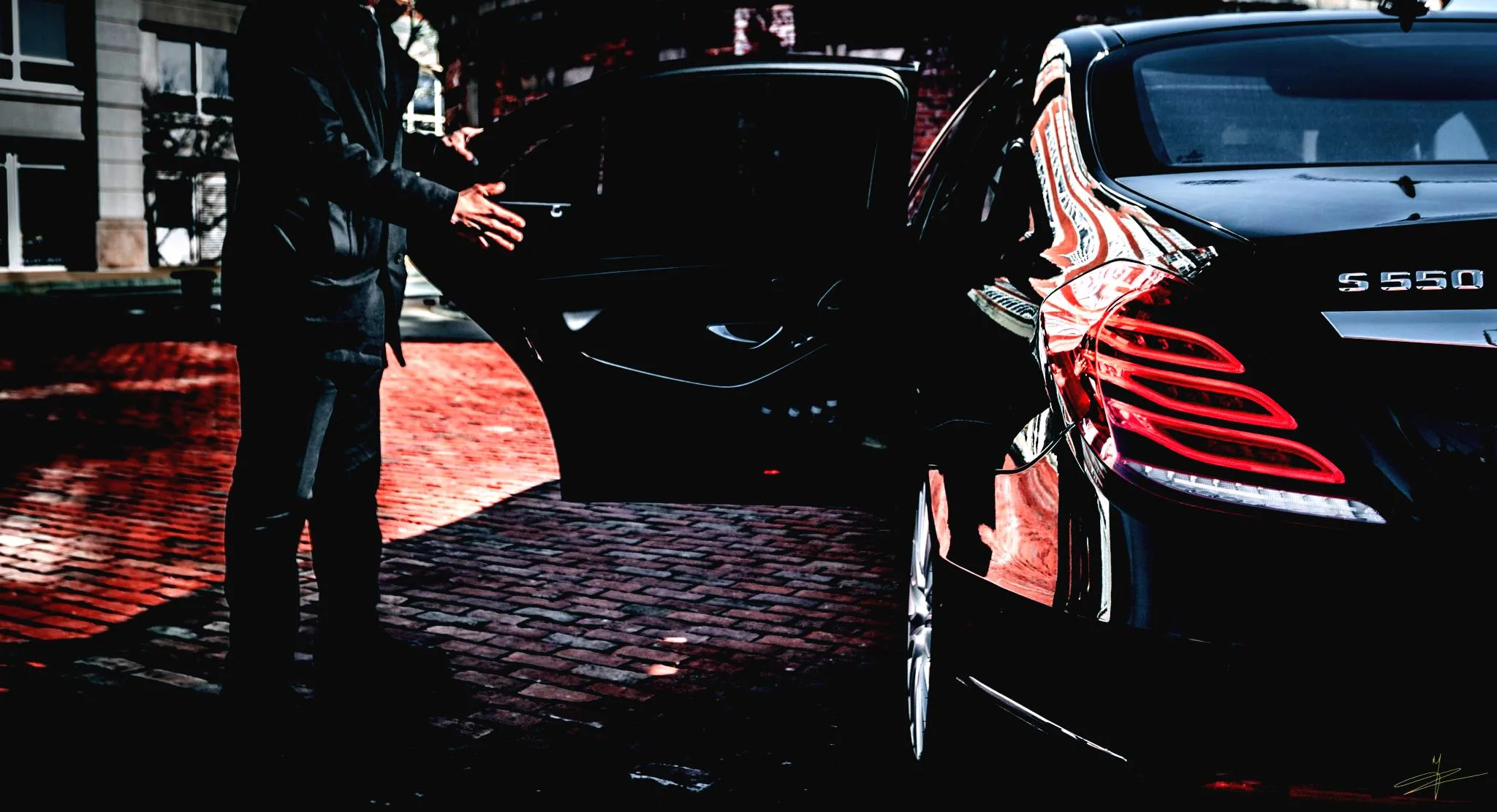 Luxury Airport Limo – St. Louis Black Limousine A chauffeur opens the door of a luxury Mercedes‑Benz S‑Class for airport limousine service in St. Louis.