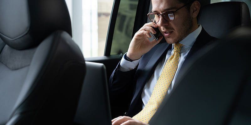 Business executive on a phone call in the back of a luxury Cadillac during an hourly chauffeur service in St. Louis.